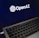 A laptop screen displaying the OpenAI logo and text. The laptop keyboard is visible below, with keys illuminated in a dimly lit environment.